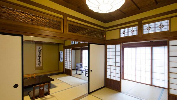 Une pièce de style japonais traditionnel, avec un sol recouvert de tatamis, des portes coulissantes et un ventilateur de plafond.