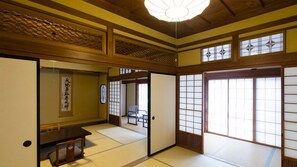 A traditional Japanese room with tatami flooring, sliding doors, and a ceiling fan.
