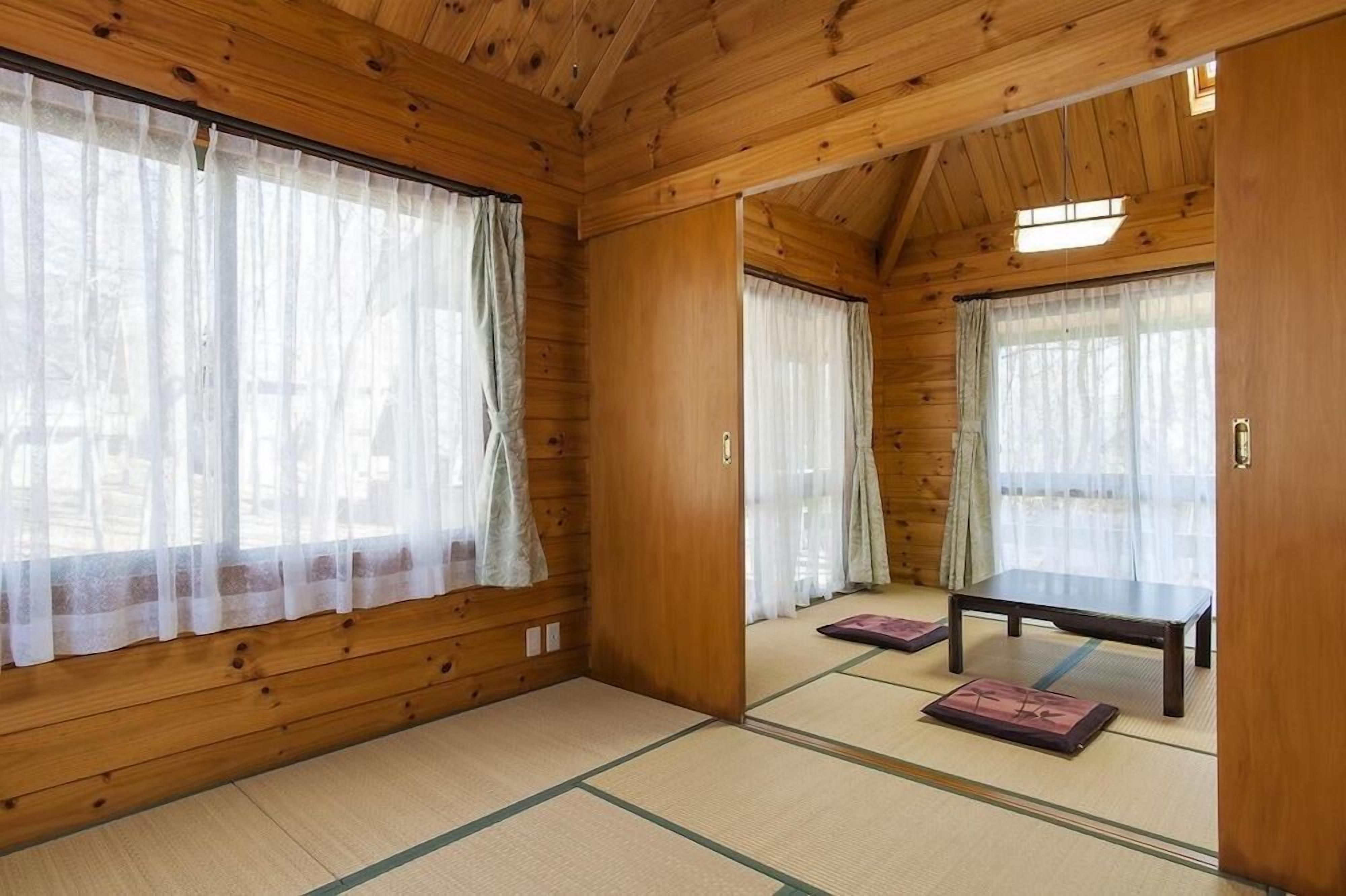 Ein traditioneller japanischer Raum mit Tatami-Boden, Schiebetüren und einem niedrigen Tisch.