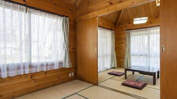 Ein traditioneller japanischer Raum mit Tatami-Boden, Schiebetüren und einem niedrigen Tisch.