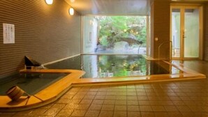 Zona de spa con hidromasaje, paredes de madera y vistas a un entorno natural al aire libre.