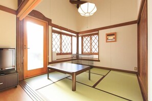 A traditional Japanese room with tatami flooring, a low table, a television, and sliding doors. - Yatsugatake Wanwan Paradise (Hokuto)