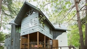 Una cabaña de madera de dos pisos con balcón y porche cubierto.