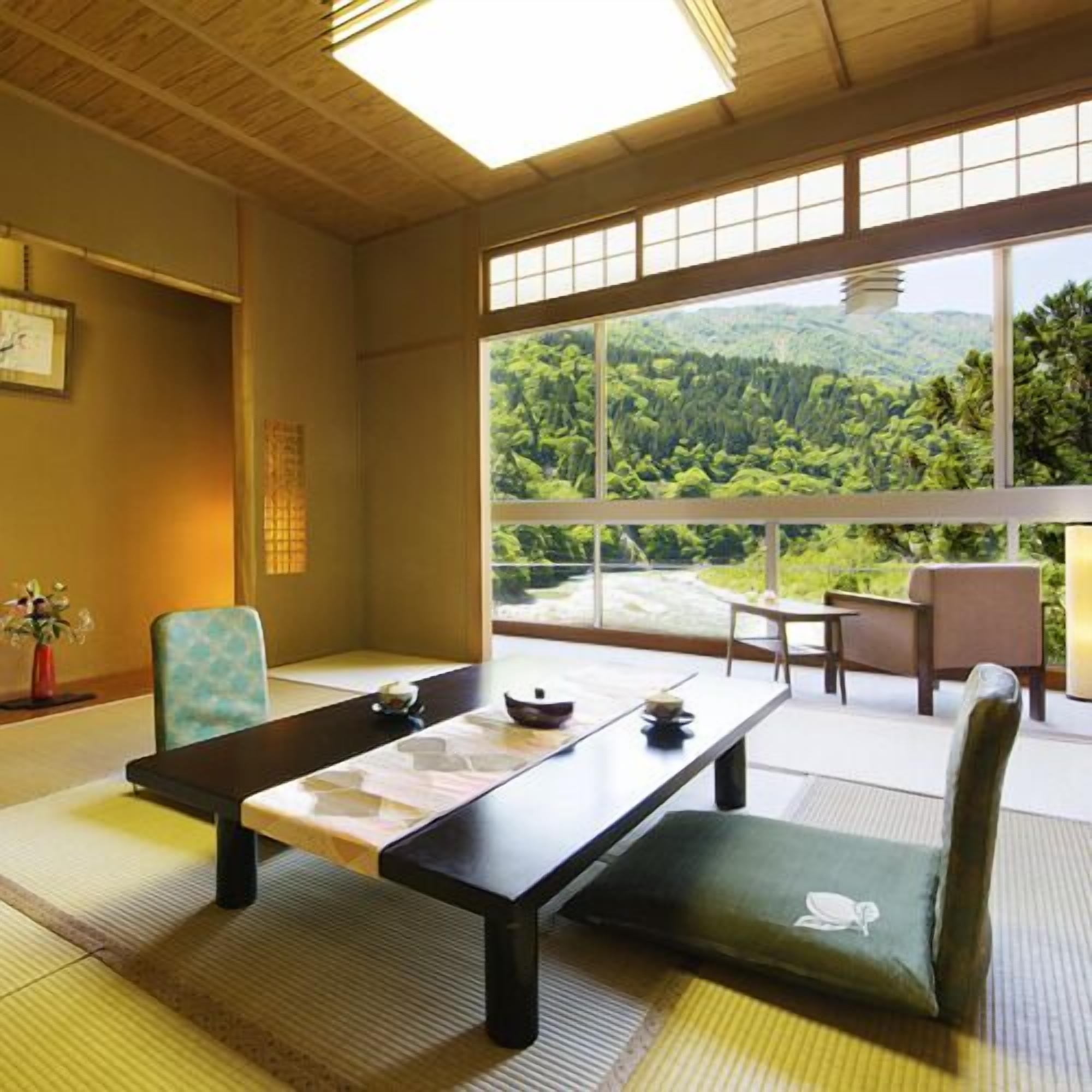 Ein traditioneller japanischer Raum mit Tatami-Böden, einem niedrigen Tisch und Blick auf einen bewaldeten Hang.
