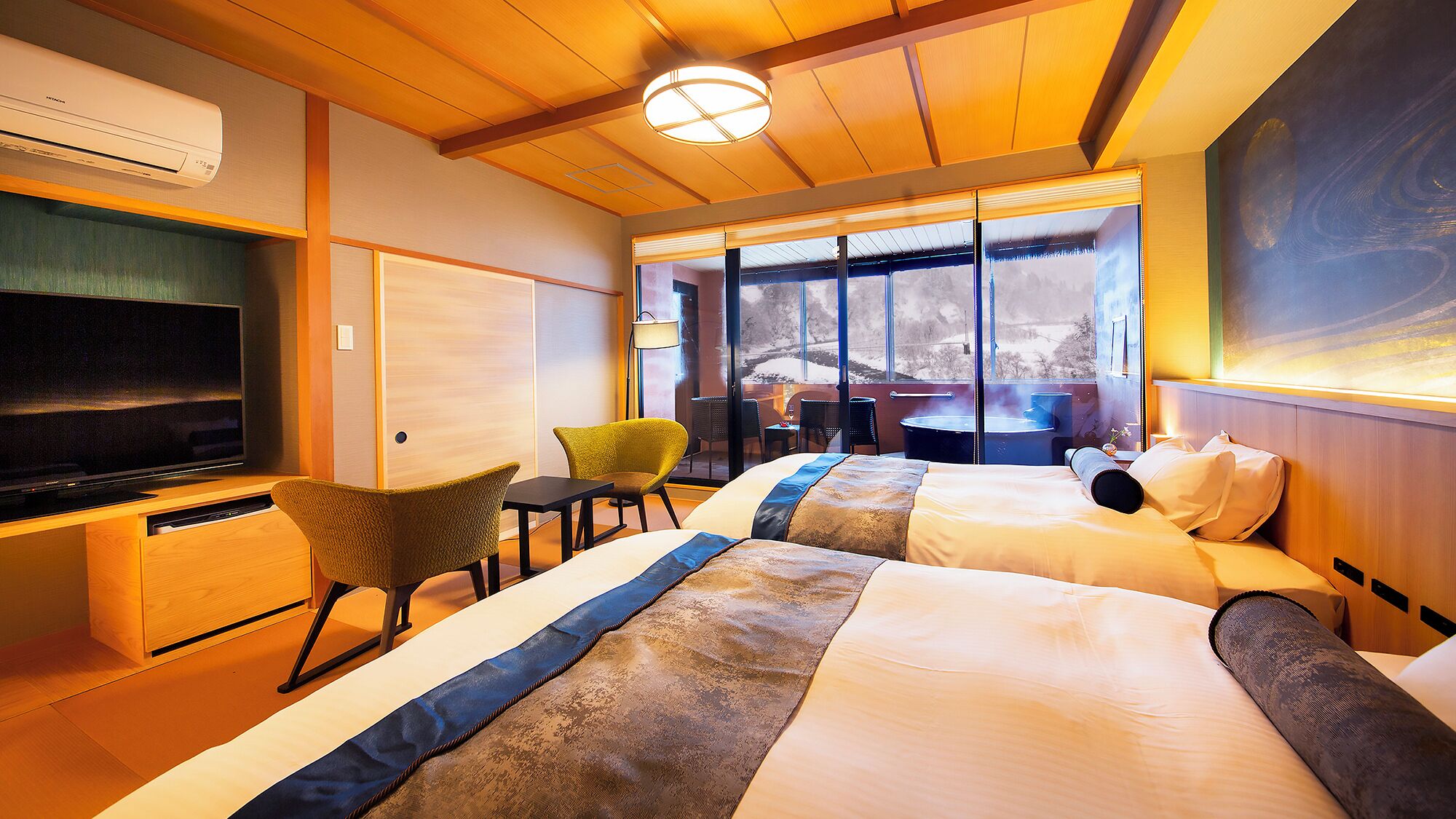 A hotel room with a TV, two beds, a sofa, a dining table, and a large window with a view.