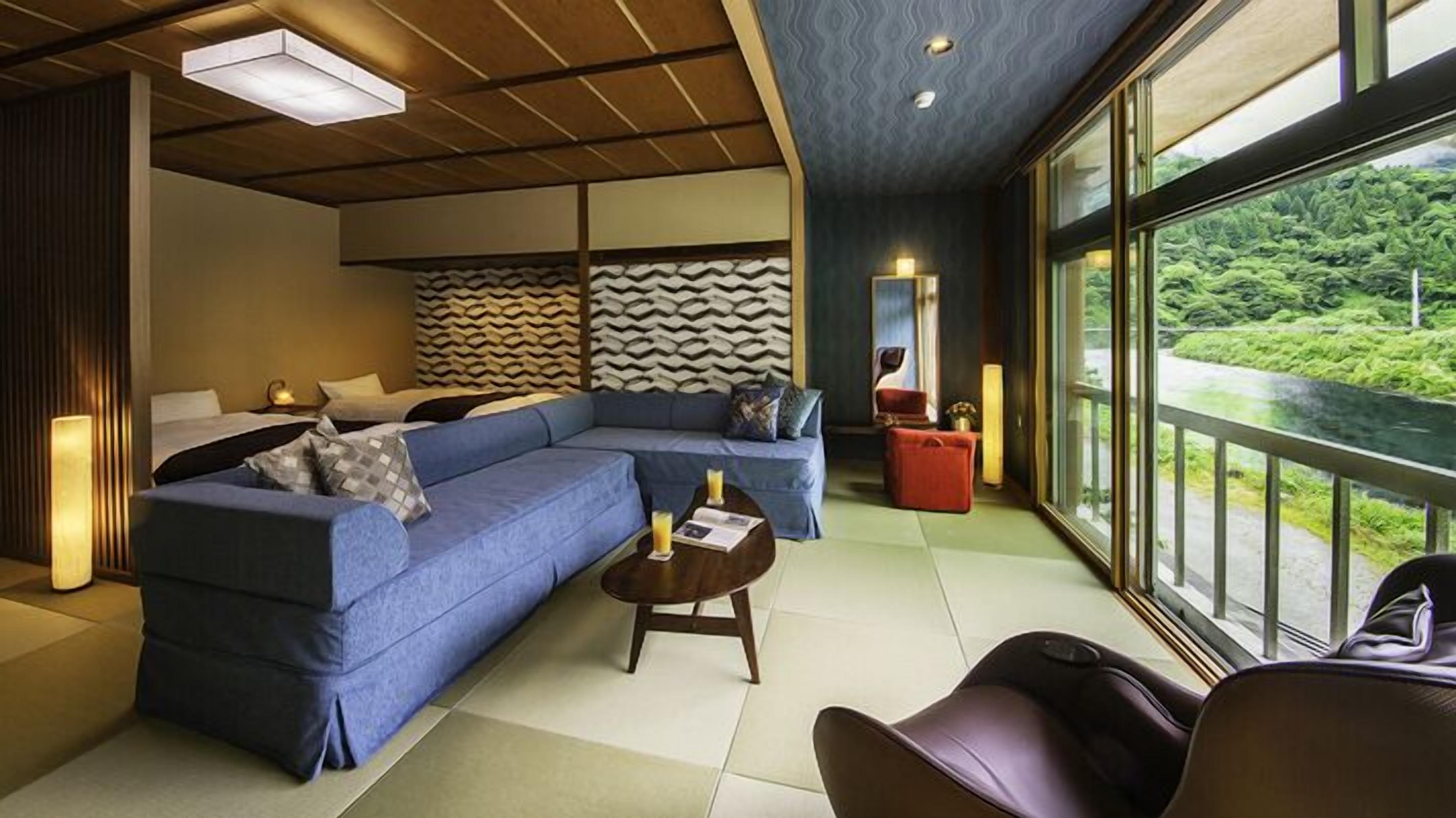 A modern living room with a sectional sofa, a coffee table, and a view of a lush landscape through large windows.