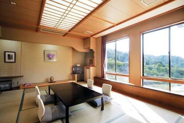 Una habitación tradicional japonesa con suelo de tatami, una mesa baja y un televisor.