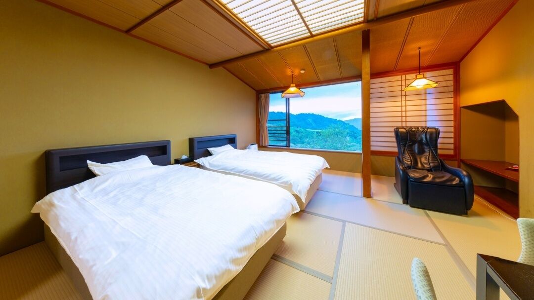 Habitación de hotel con dos camas, una silla y vistas a las montañas, con una decoración interior tradicional japonesa.