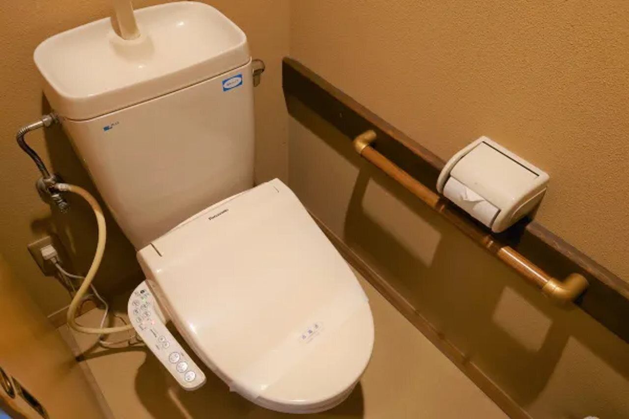 Une salle de bain d’hôtel standard, équipée de toilettes, d’un bidet et d’un sèche-mains.