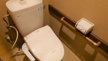Une salle de bain d’hôtel standard, équipée de toilettes, d’un bidet et d’un sèche-mains.