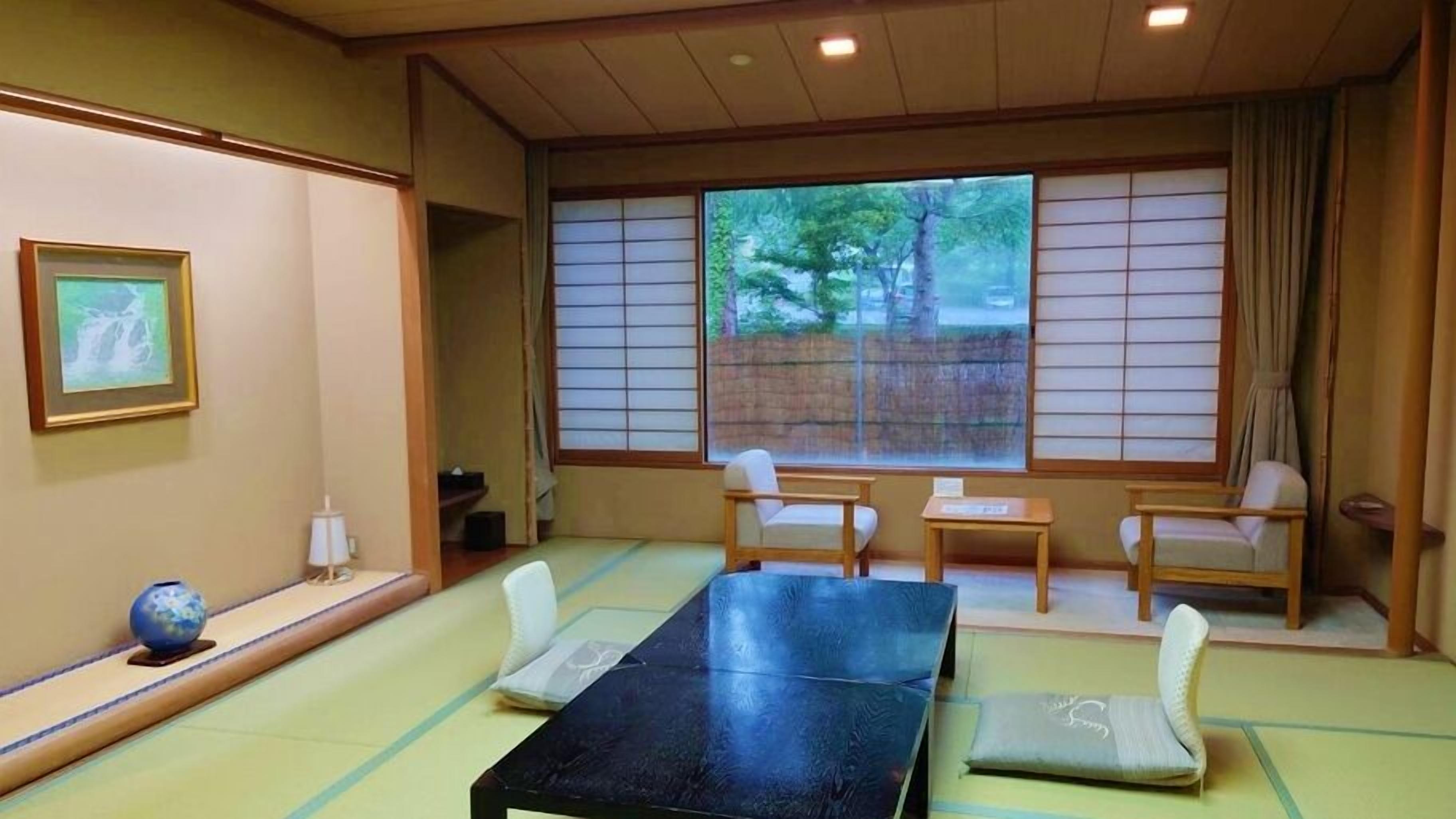 Una habitación japonesa tradicional con suelo de tatami, una mesa baja y puertas correderas.