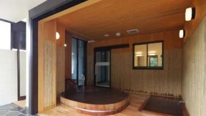Un interior moderno con una plataforma circular de madera, suelo de piedra y techo de madera.