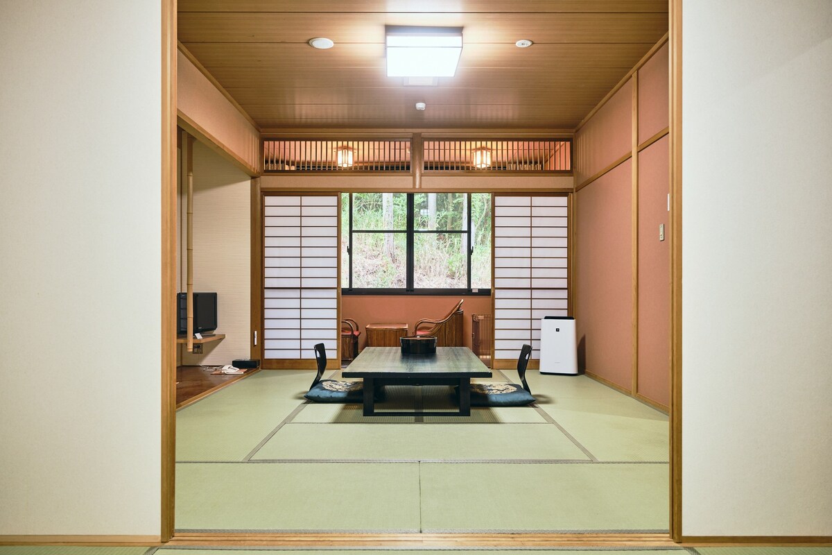 A traditional Japanese room with tatami flooring, a low table, and sliding doors.