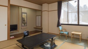 A traditional tatami mat room with a tatami mat table, a television, and a window with a view. - Sugatani Onsen (Nagahama)