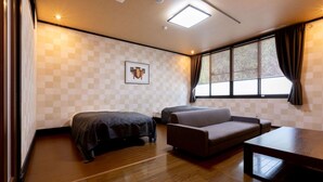 A hotel room with a bed, sofa, and a table. - Sugatani Onsen (Nagahama)
