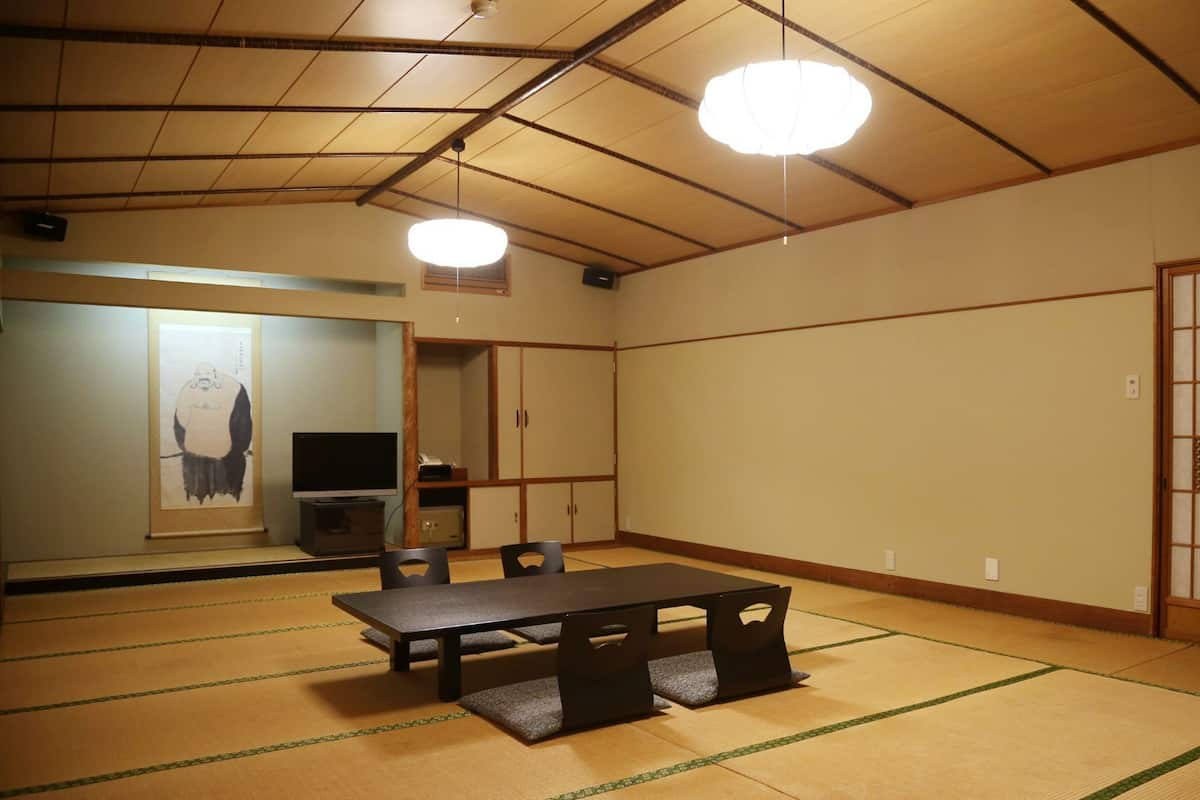 A traditional Japanese room with tatami flooring, a tatami mat table, a television, and a shoji screen.