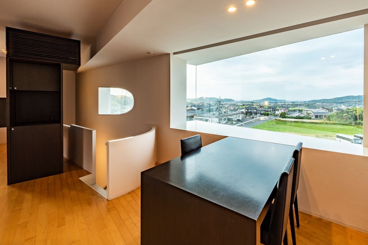 A modern room with a large window, a built-in desk, and a view of a cityscape.