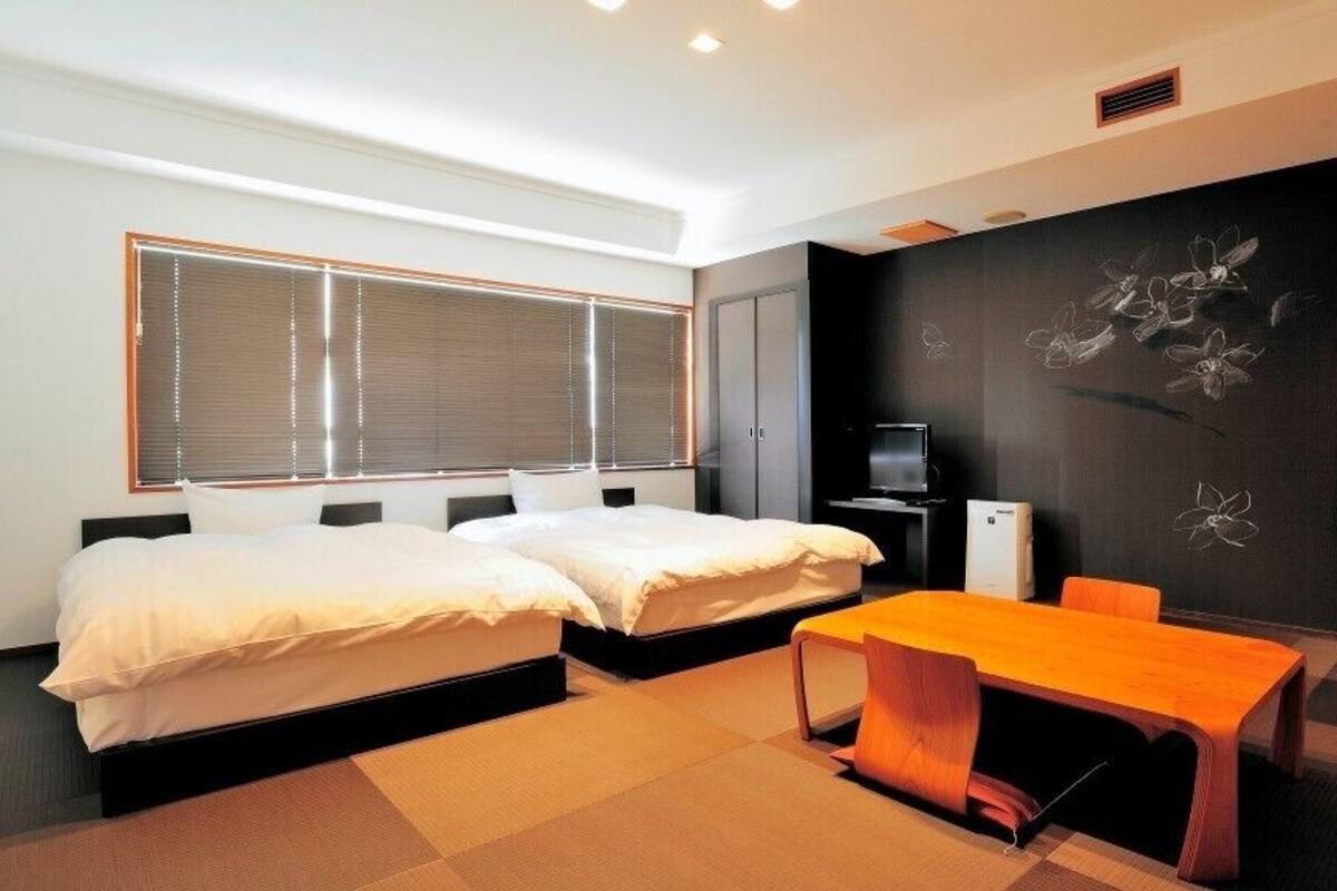 A modern hotel room with two beds, a desk, and a television.
