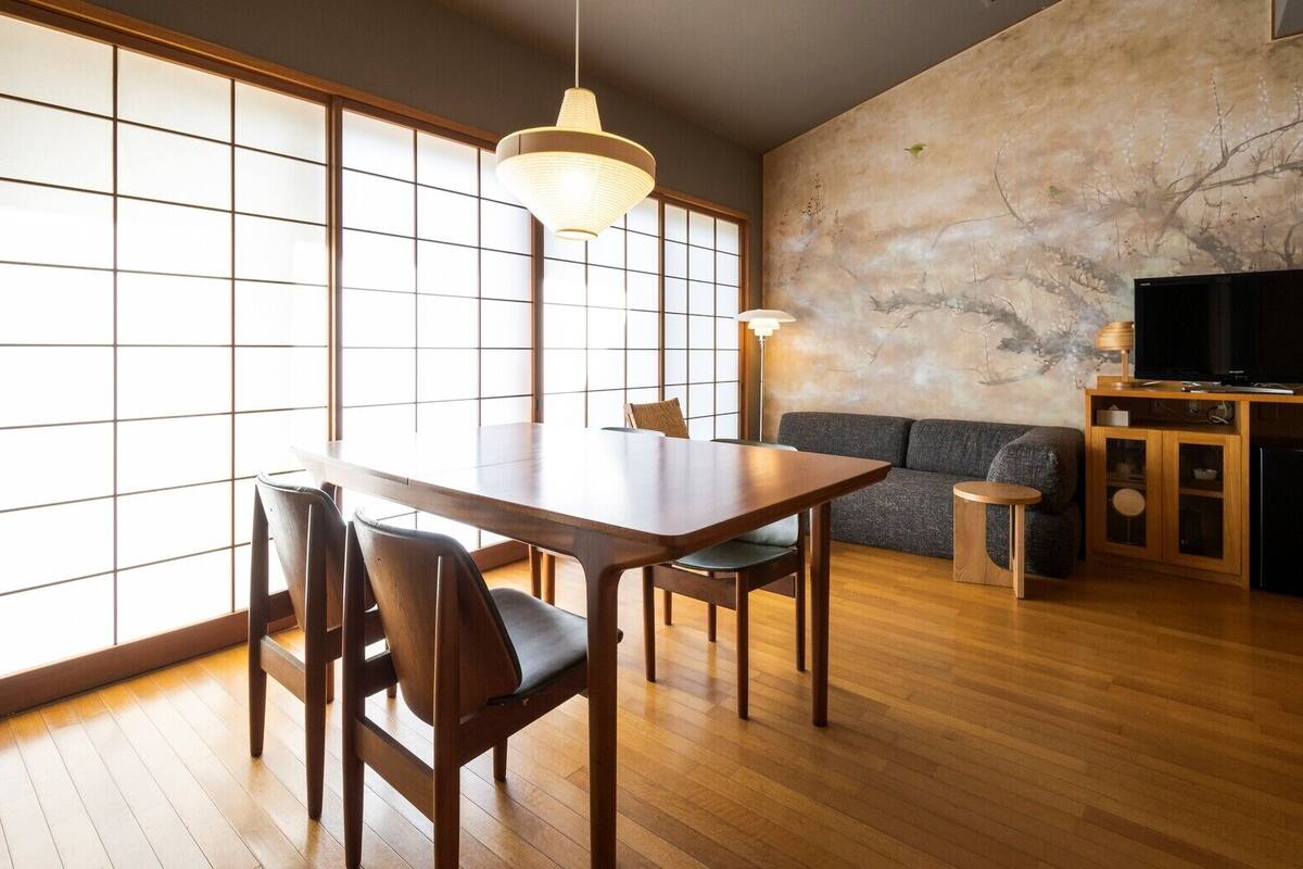 A modern living room with a dining table, chairs, a sofa, a TV, and a cabinet.