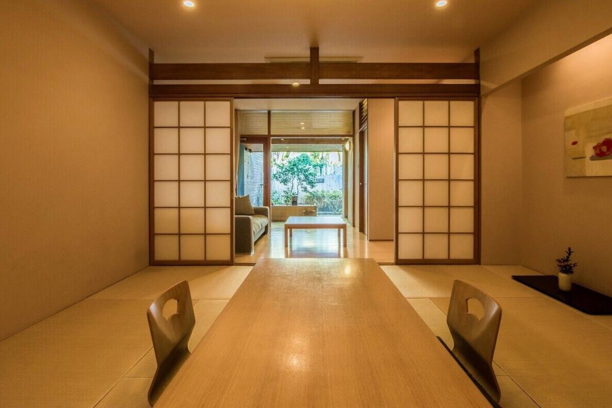 A traditional Japanese room with tatami flooring, a low table, and sliding doors leading to a garden.