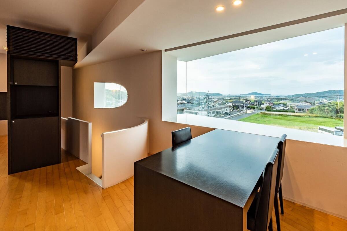 A modern room with a large window, a built-in desk, and a view of a cityscape.