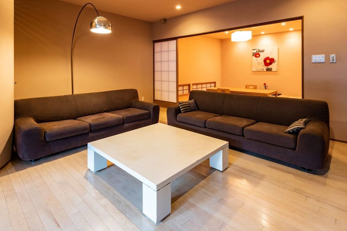 A living room with two sofas, a coffee table, a lamp, a sliding door, and a painting on the wall.