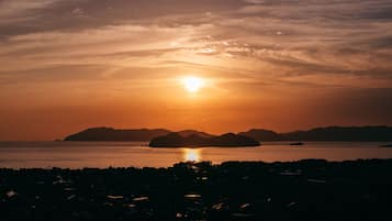 A sunset over a body of water with distant landforms.