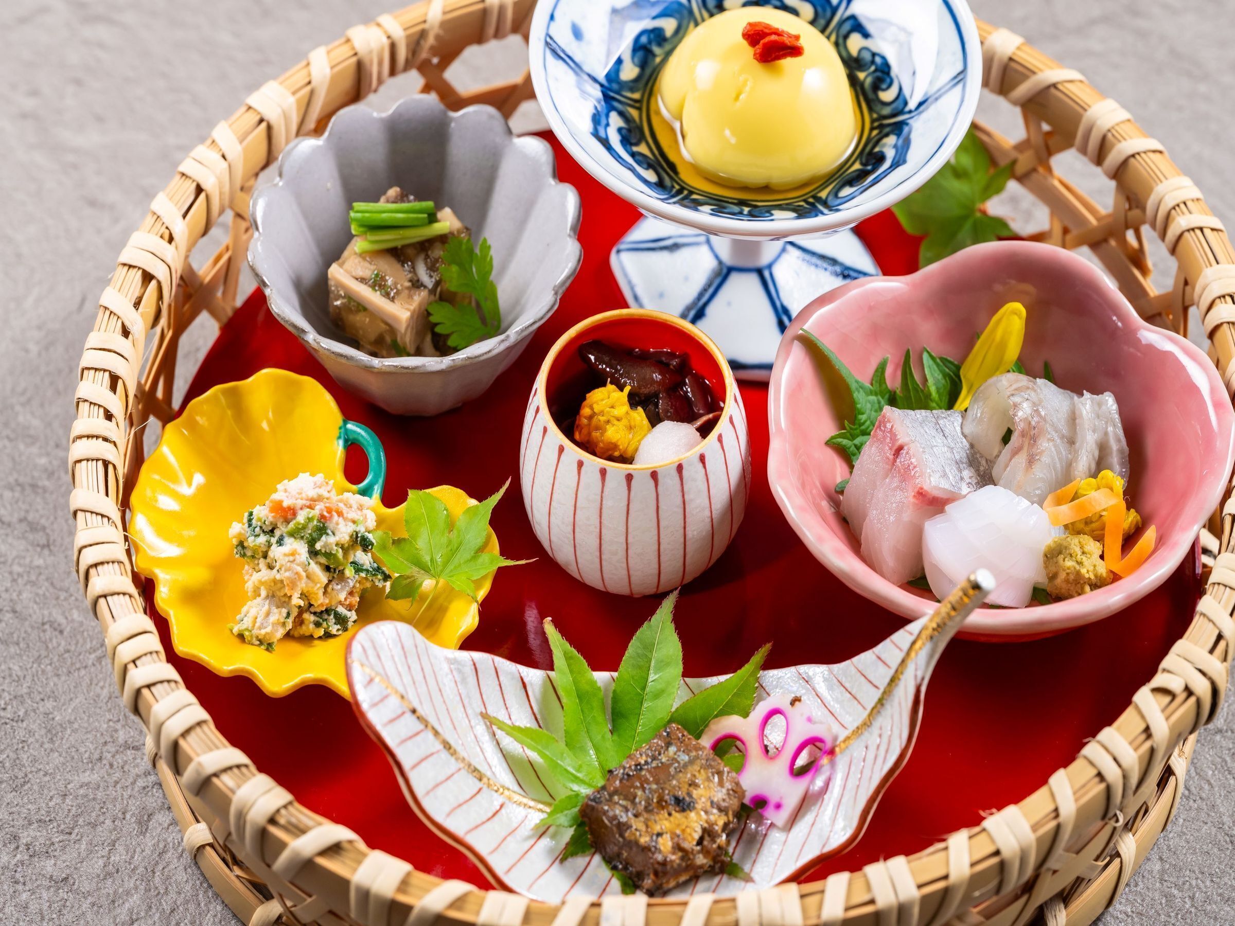 A traditional Japanese meal with various dishes on a woven tray.