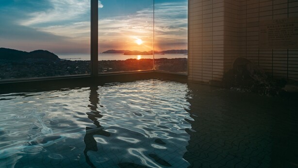 Ein Whirlpool mit Blick auf den Sonnenuntergang über einer Stadtlandschaft.