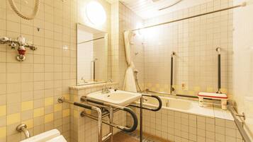 A bathroom with a sink, mirror, shower, and grab bars.