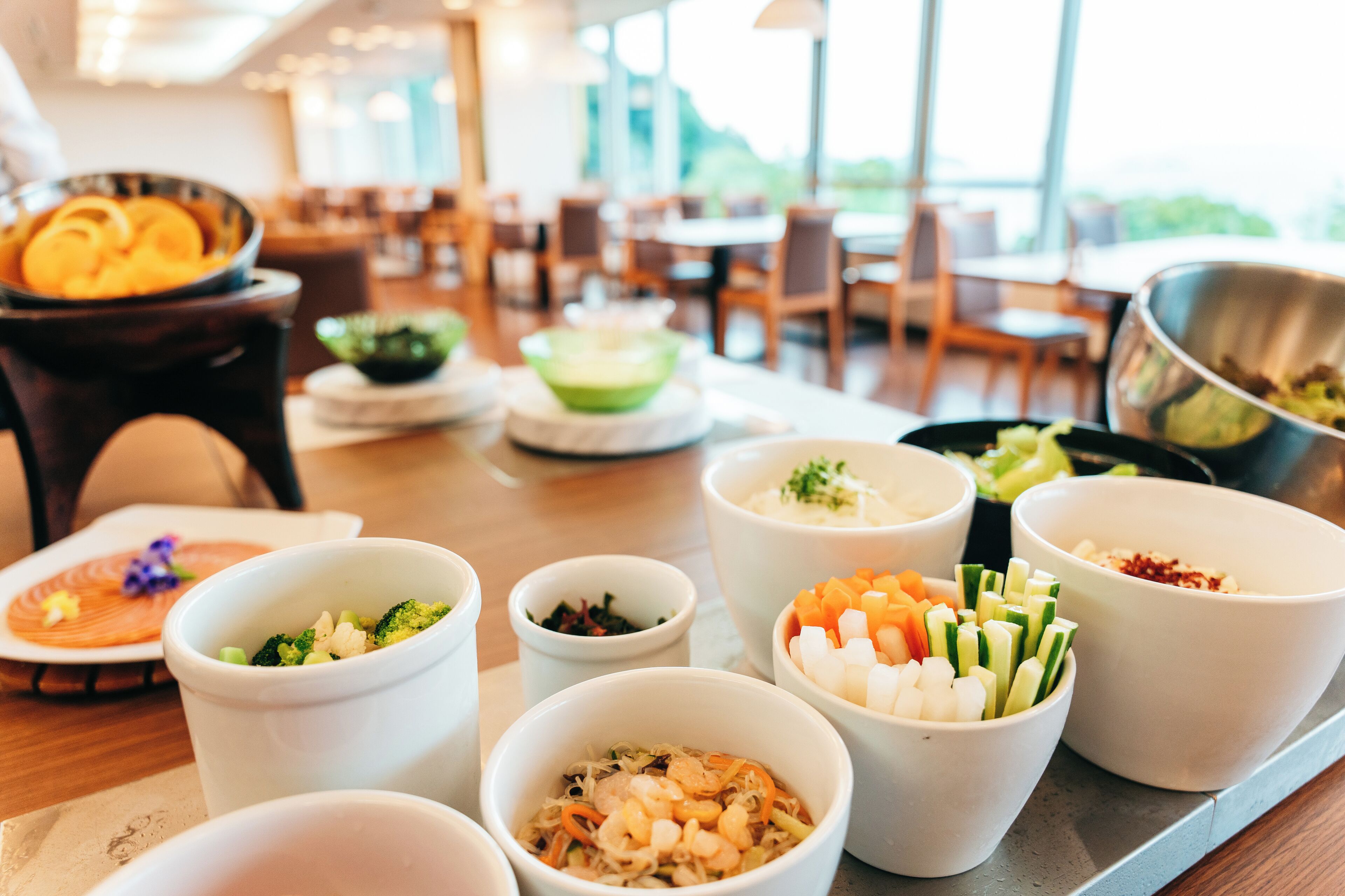 A buffet table with various food items in bowls, including vegetables and seafood.