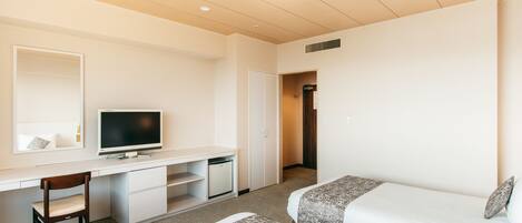A hotel room with a desk, two beds, a television, and a wardrobe.