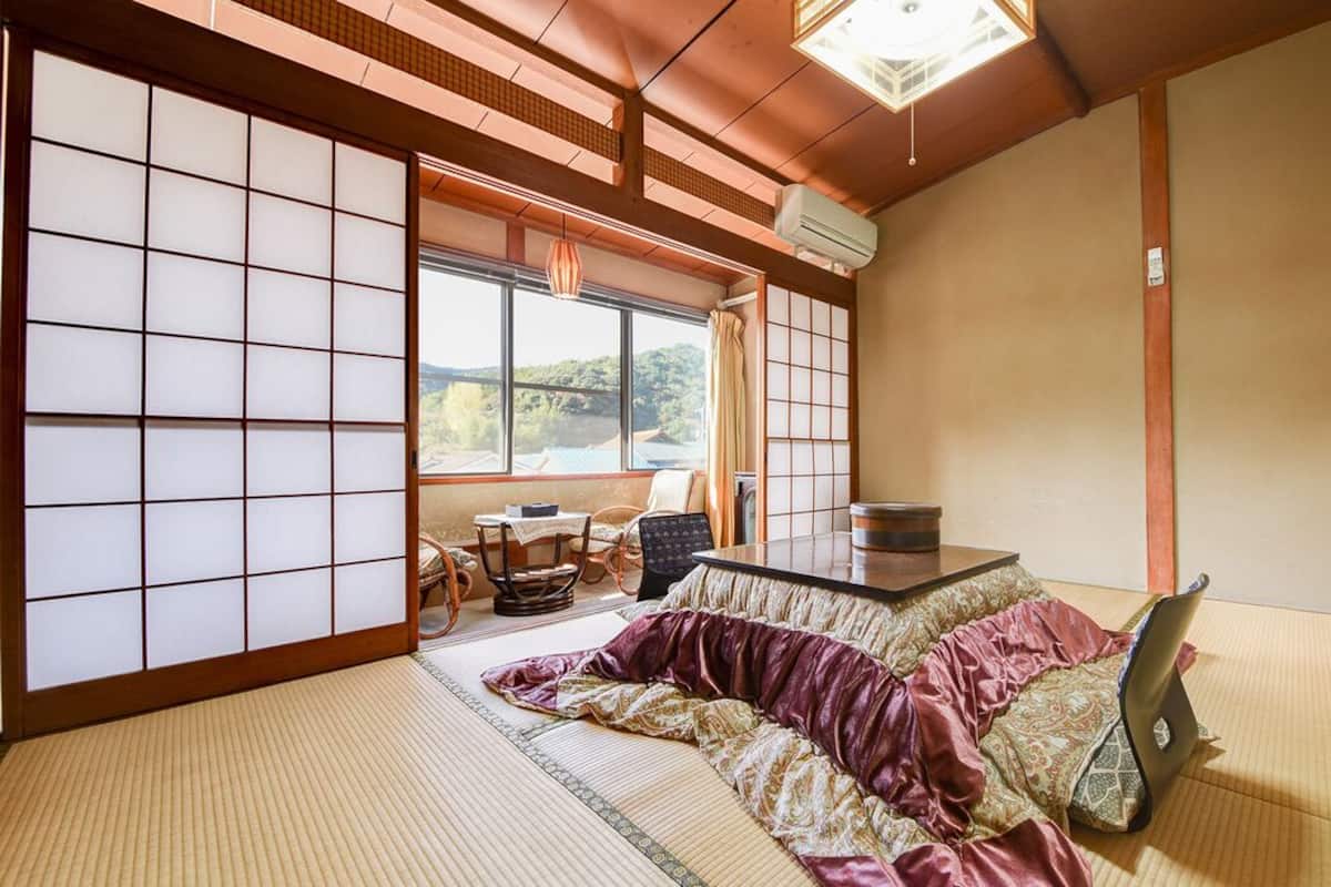 A tatami mat room with a sliding door, a table, and a view of the outdoors.
