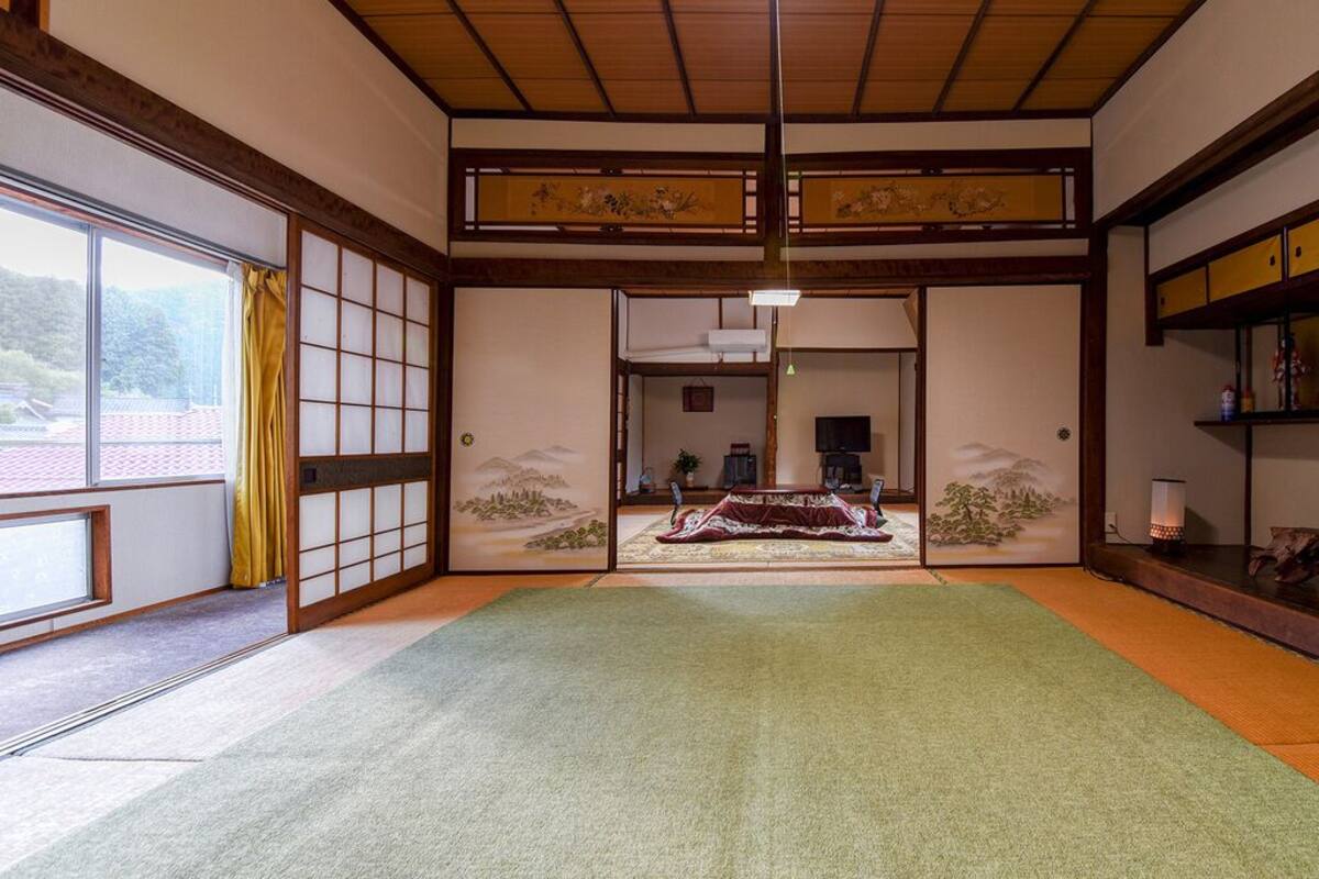 A traditional Japanese room with tatami flooring, sliding doors, and a view through a shoji screen.