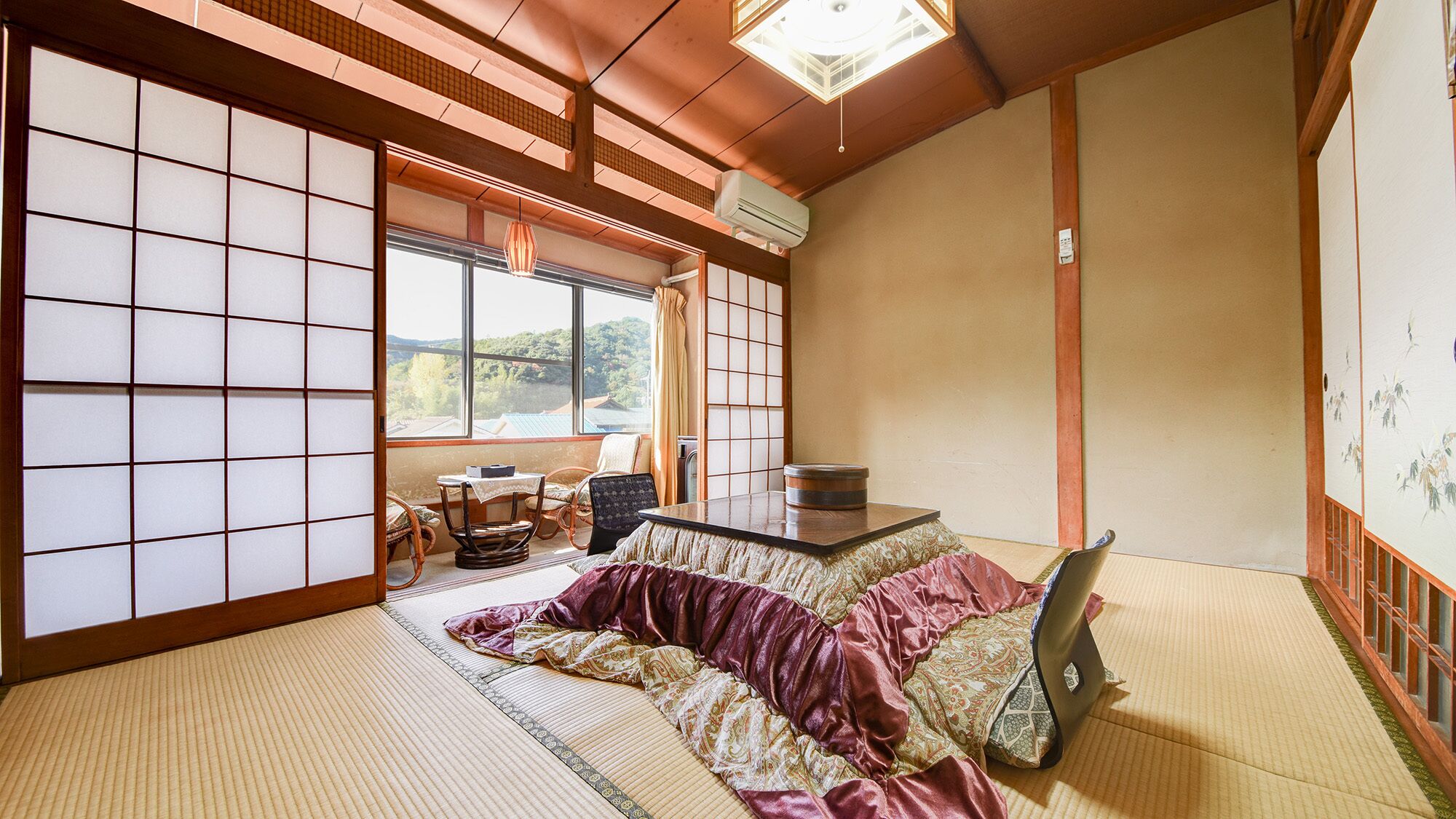 Una habitación tradicional japonesa con suelo de tatami, futón, una mesa baja con juego de té y una puerta corredera shoji.