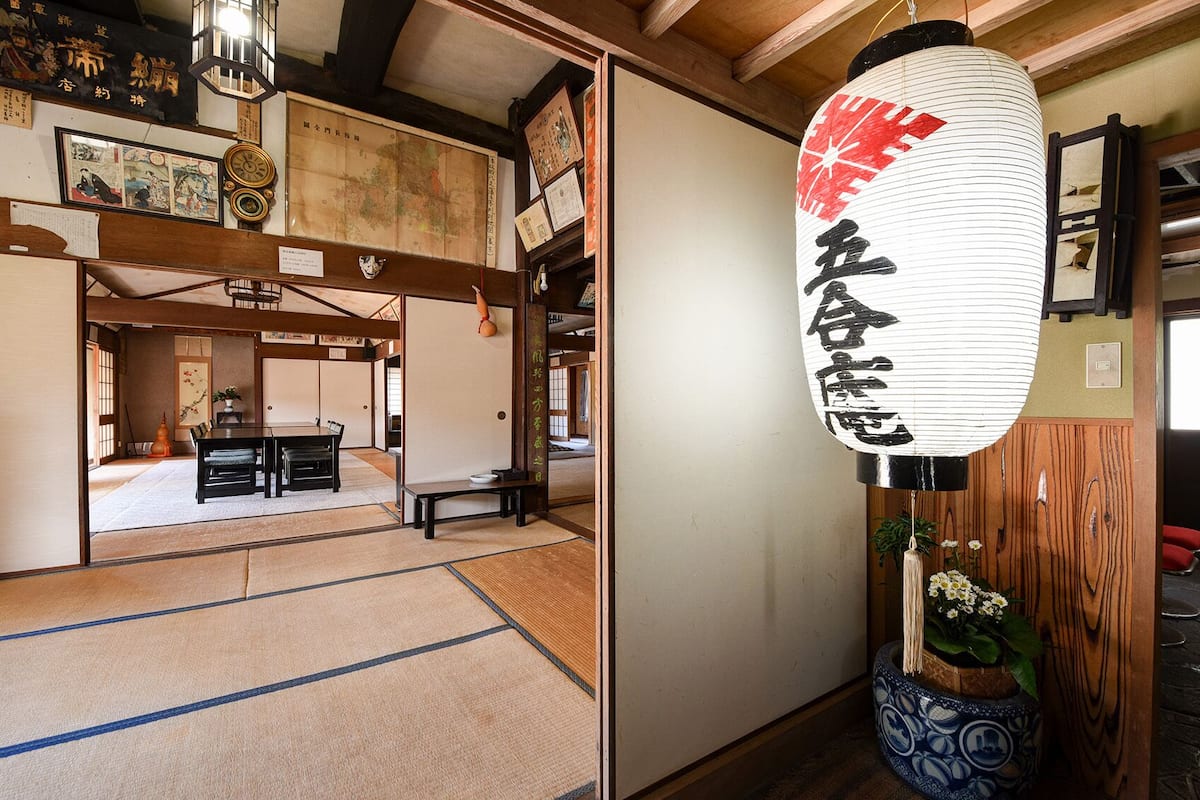 A traditional Japanese room with tatami flooring, a shoji screen door, and a hanging lantern.