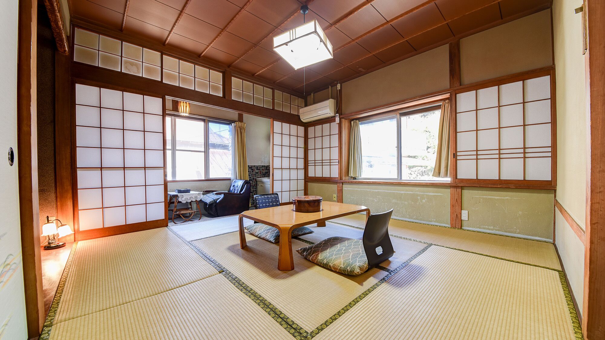 Una habitación japonesa tradicional con suelo de tatami, una mesa baja y puertas correderas.