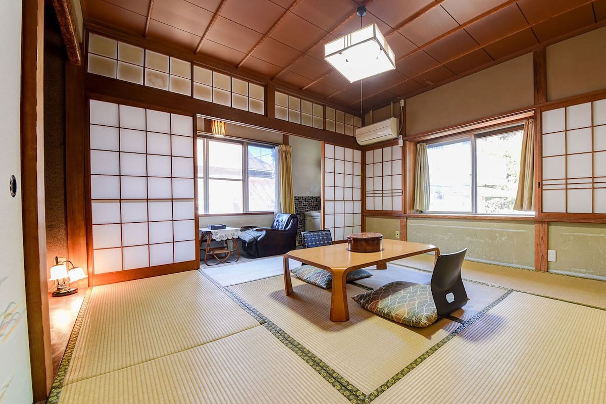 A traditional Japanese room with tatami flooring, a low table, and sliding doors.