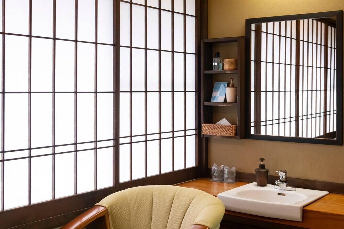 Et traditionelt japansk badeværelse med et stort vindue, en vask og et spejl.