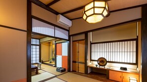 A traditional Japanese room with tatami flooring, sliding doors, a ceiling fan, and a decorative lantern.