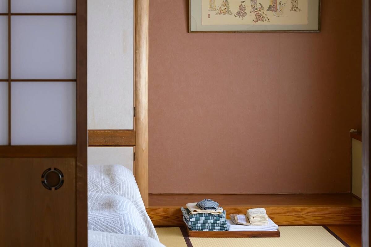 Et traditionelt japansk rum med tatamimåtter, en shoji skærmdør og en futon seng.