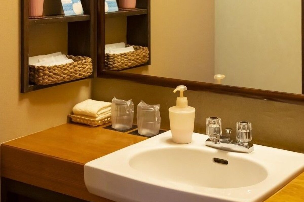 Un bagno con un lavandino bianco, uno specchio e ripiani con articoli da toilette.