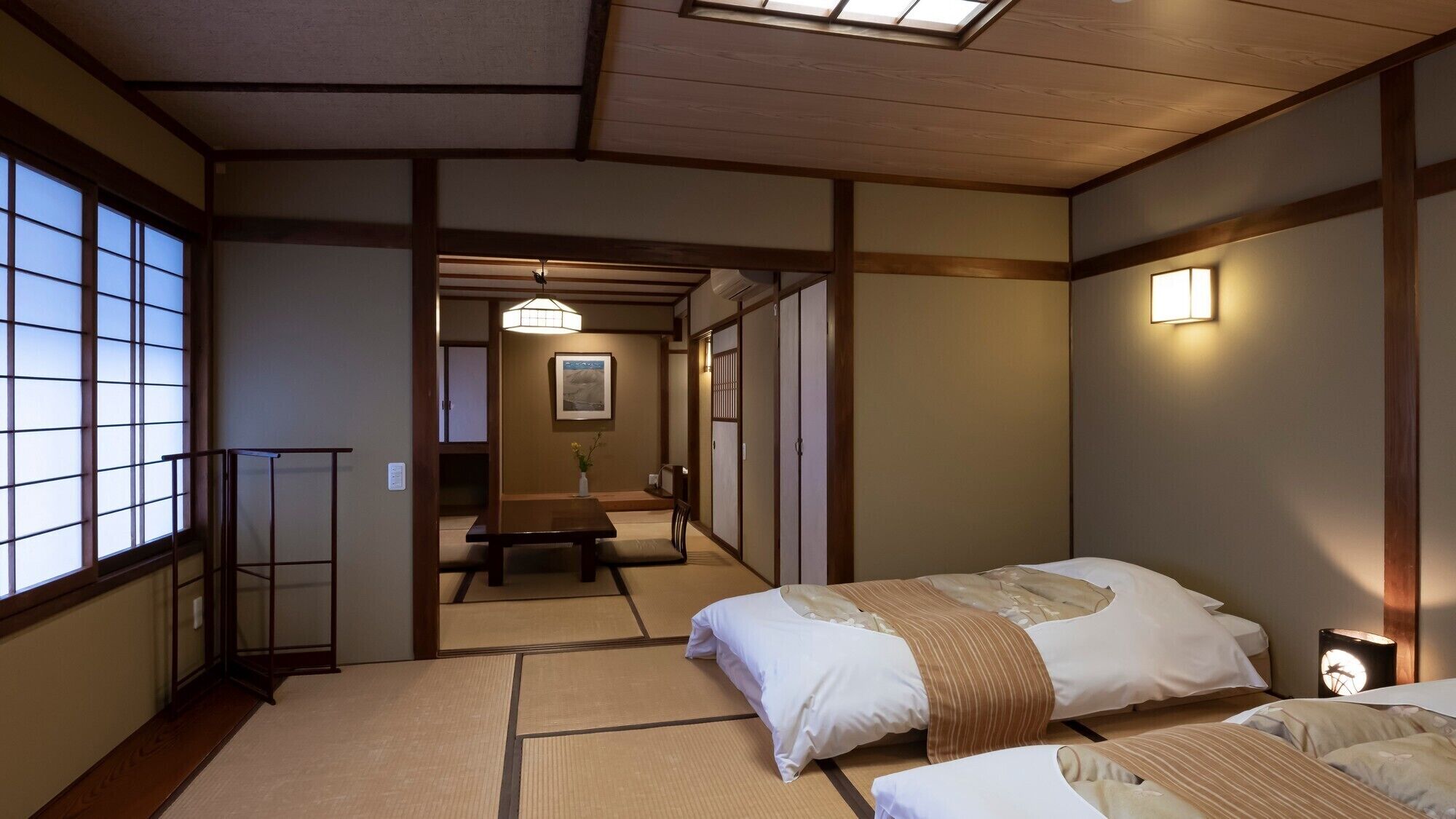 Una habitación tradicional japonesa con suelo de tatami, una cama baja de madera y una puerta corredera.