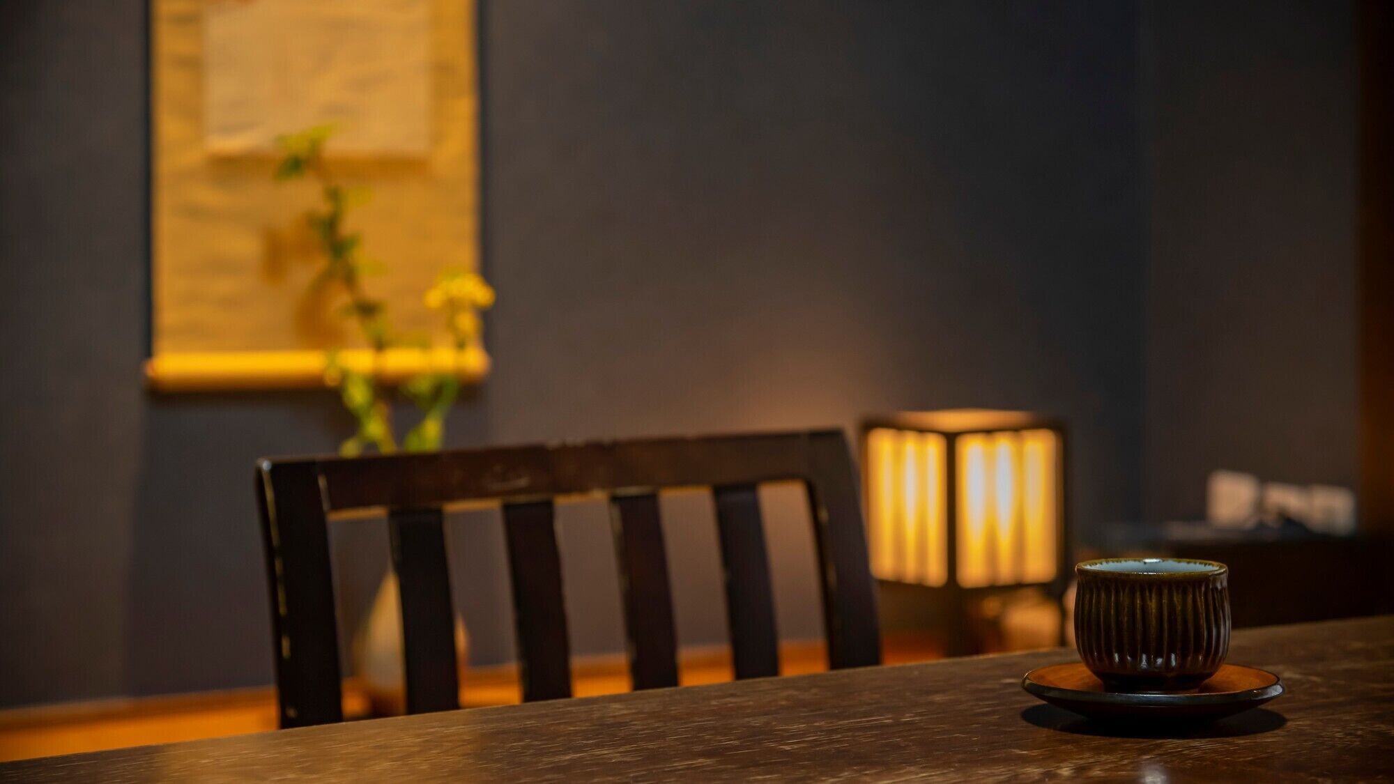 Una mesa de comedor con una silla, una vela y un florero con flores.
