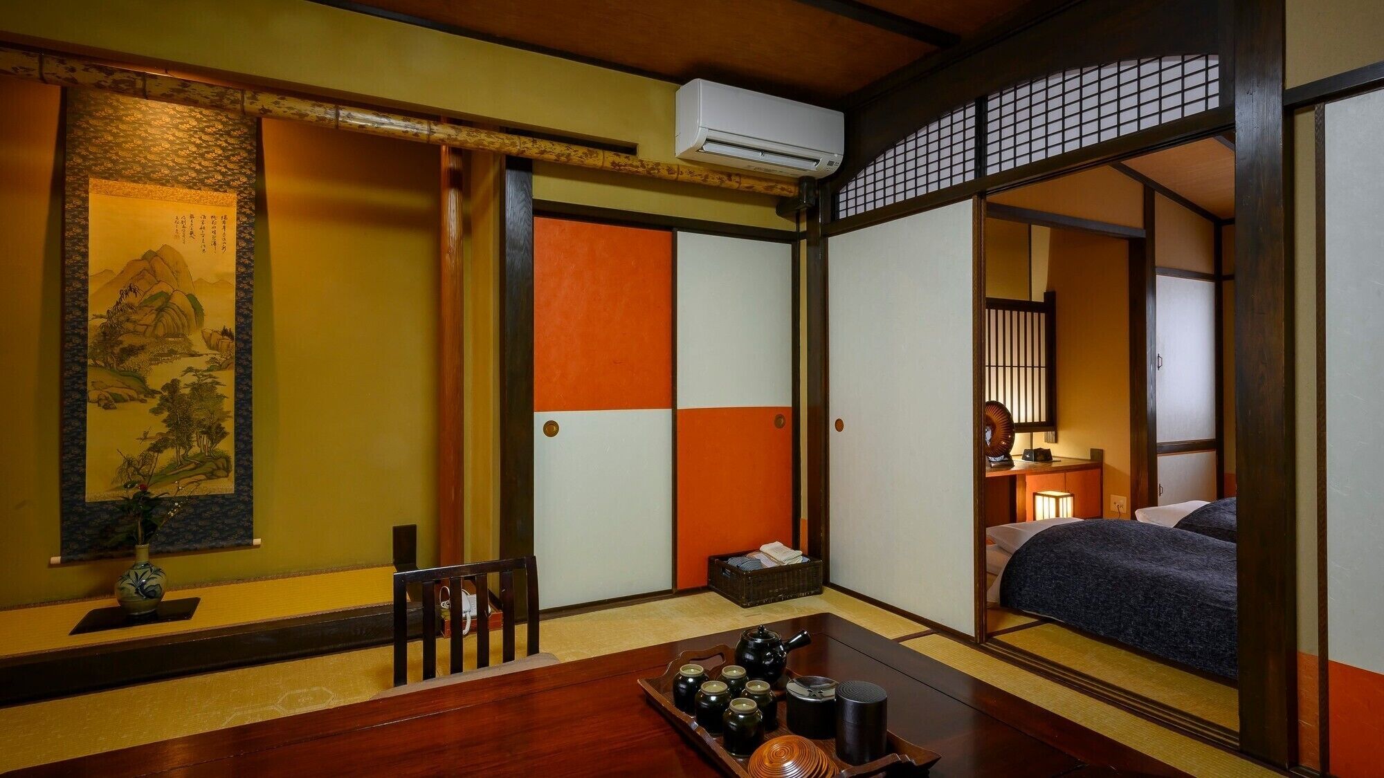 Perinteinen japanilainen huone, jossa on tatamimatto, shoji-liukuovi, futon-patja, teekuppisarja ja kalligrafiakirjoituksella koristeltu seinäkaide.