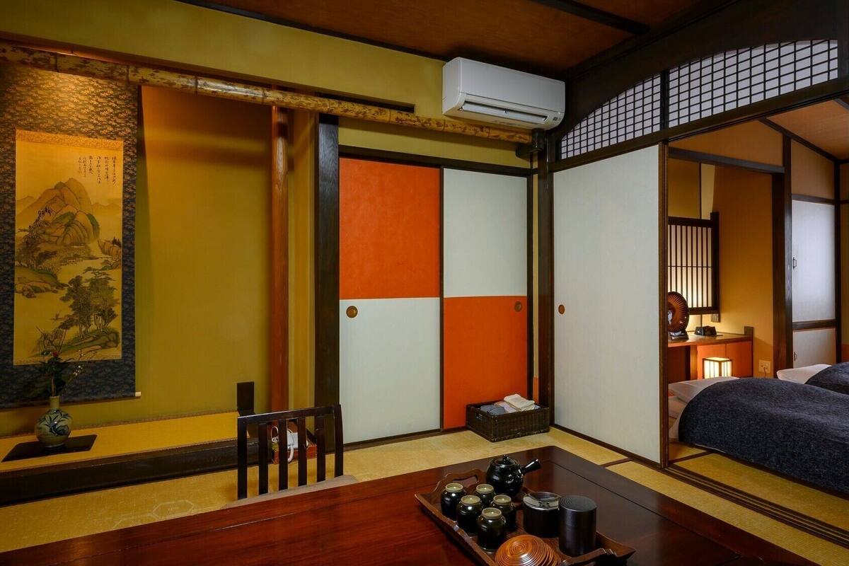Et traditionelt japansk rum med tatamigulv, en shoji-skærm, en futon-madras, et tesæt og en kalligrafisk rulle.
