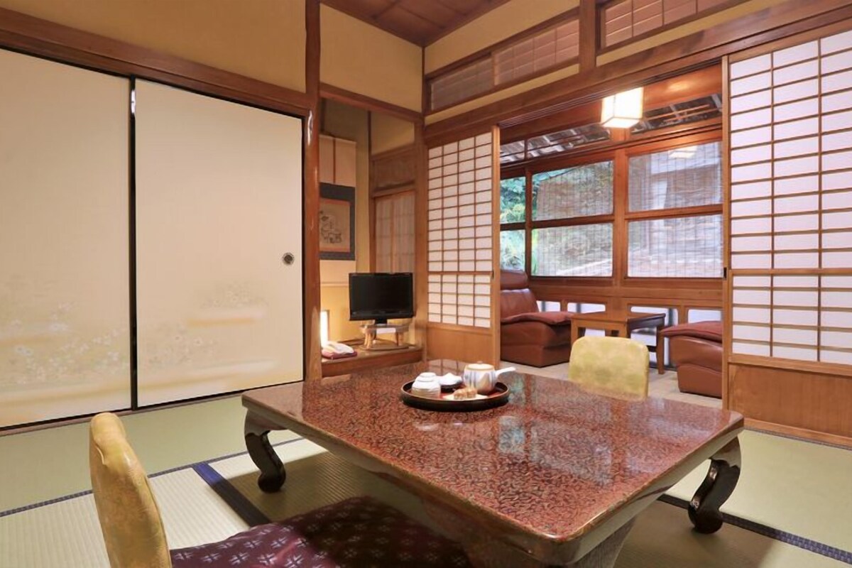 Una stanza tradizionale giapponese con pavimento in tatami, un tavolino con un vassoio di tè e porte scorrevoli.