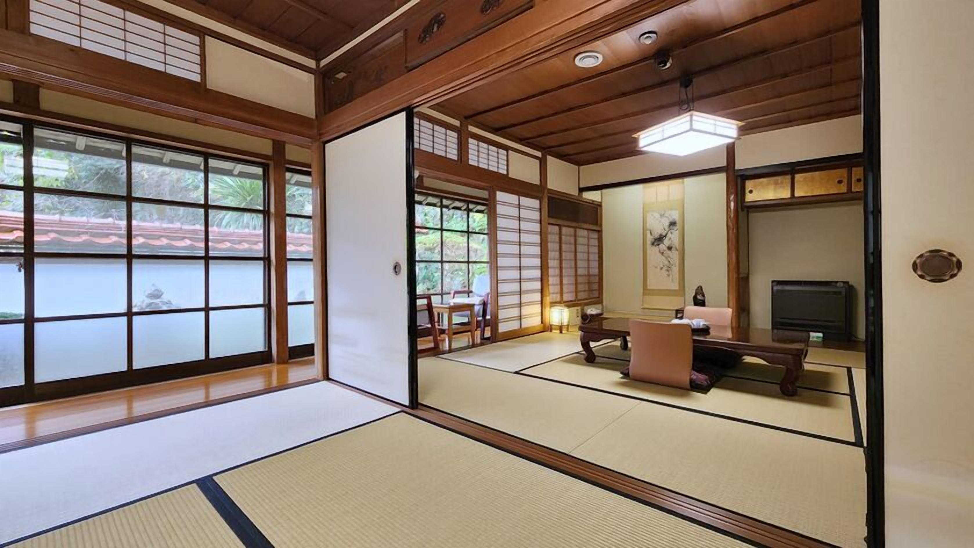 Una habitación japonesa tradicional con suelo de tatami, puertas correderas y un televisor.