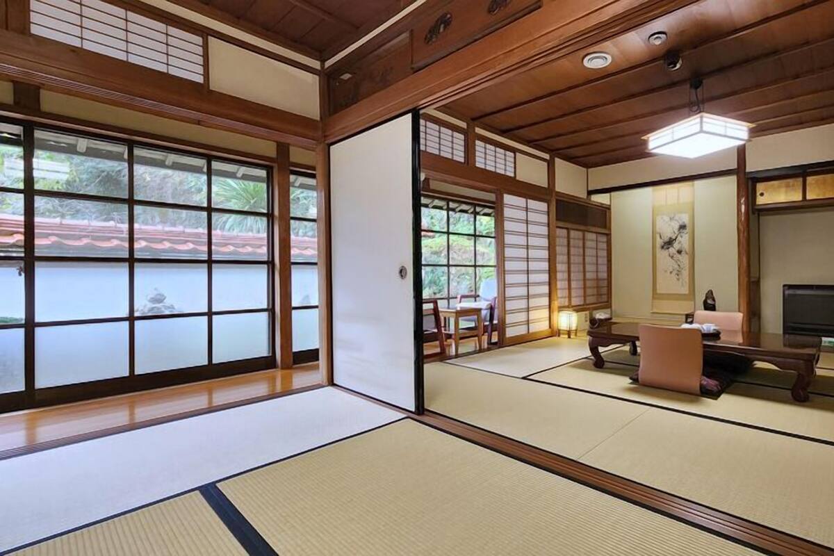 Une pièce de style japonais traditionnel, avec un sol recouvert de tatamis, des portes coulissantes et un téléviseur.