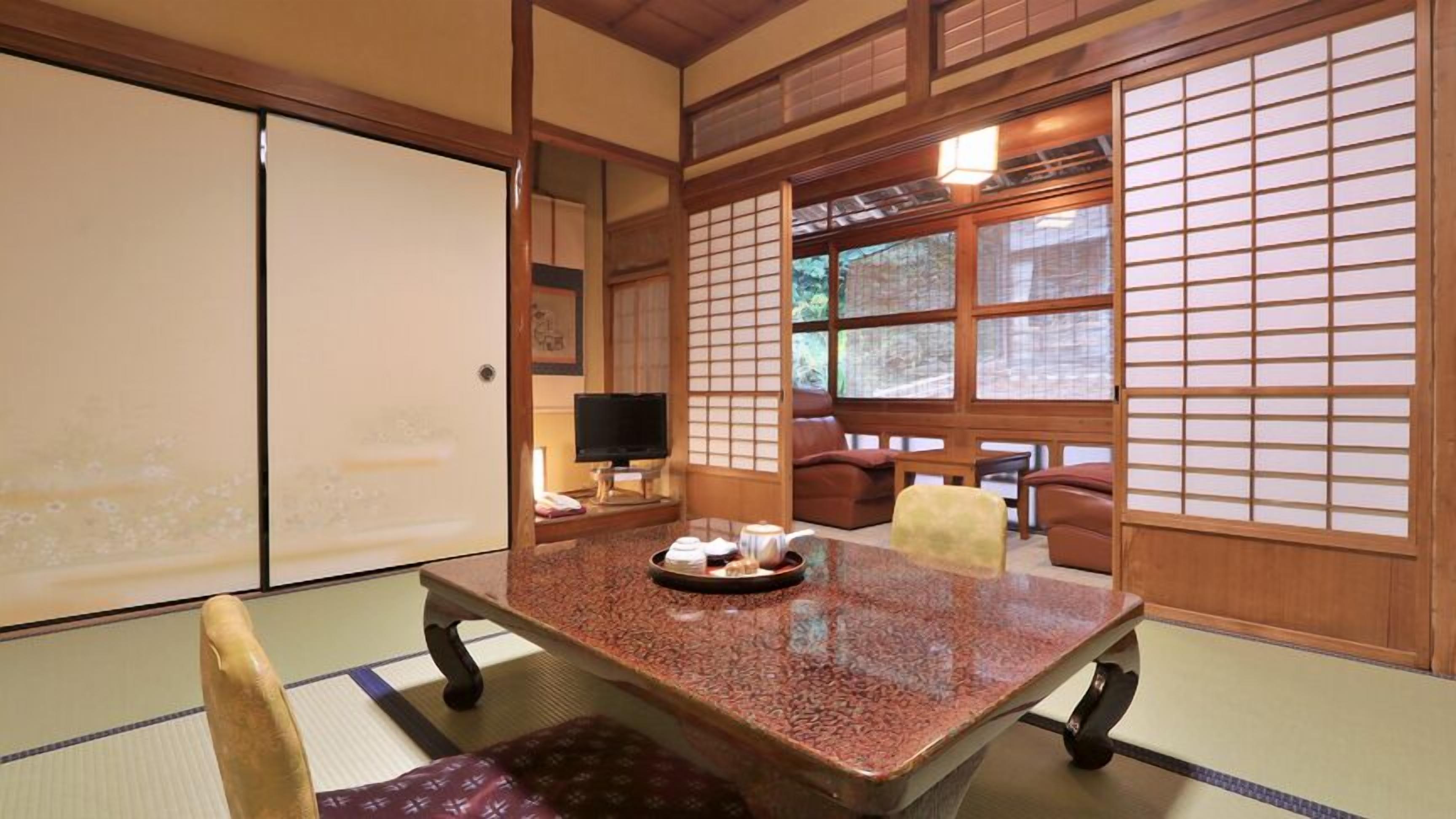 Una habitación tradicional japonesa con suelo de tatami, una mesa baja con una bandeja de té y puertas correderas.